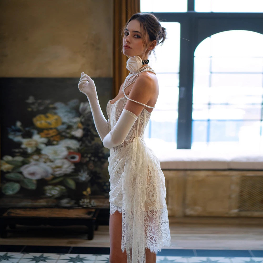 Side angle of a strapless mini bridal gown highlighting an open-weave lace pattern, a structured corset profile, and a cascading sheer lace side train layout.
