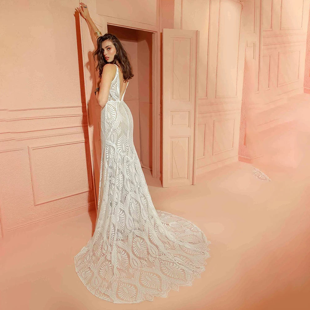 Full length rear view of the bohemian lace mermaid wedding dress in a warm-toned studio setting, displaying the intricate pattern of the long lace train spread across the floor.