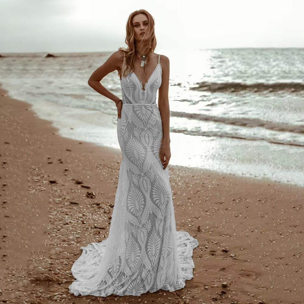 Beautiful front profile of the sexy lace V-neck beach mermaid wedding gown on the seashore, accentuating the high-end geometric lace design perfect for an outdoor destination wedding.