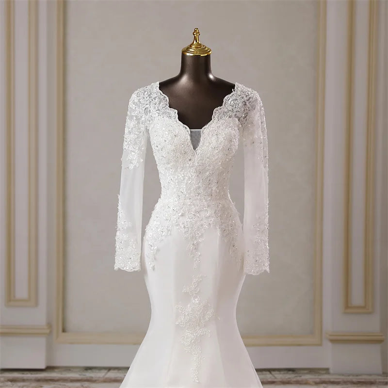 A close-up view of the sophisticated V-neckline and intricate lace applique details on the bodice of the long-sleeved mermaid bridal gown.