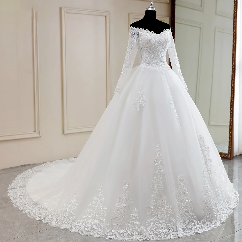 A close-up view of the bodice of a sexy, long-sleeve, off-shoulder lace bridal gown, highlighting intricate beading and floral lace details.