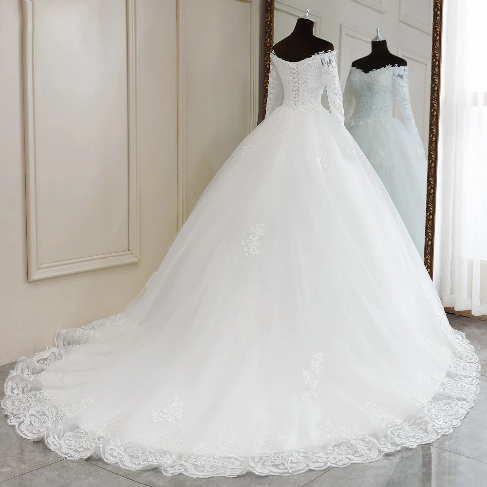 A mannequin displaying the full silhouette of an elegant long-sleeve, off-shoulder lace wedding dress with a dramatic train.