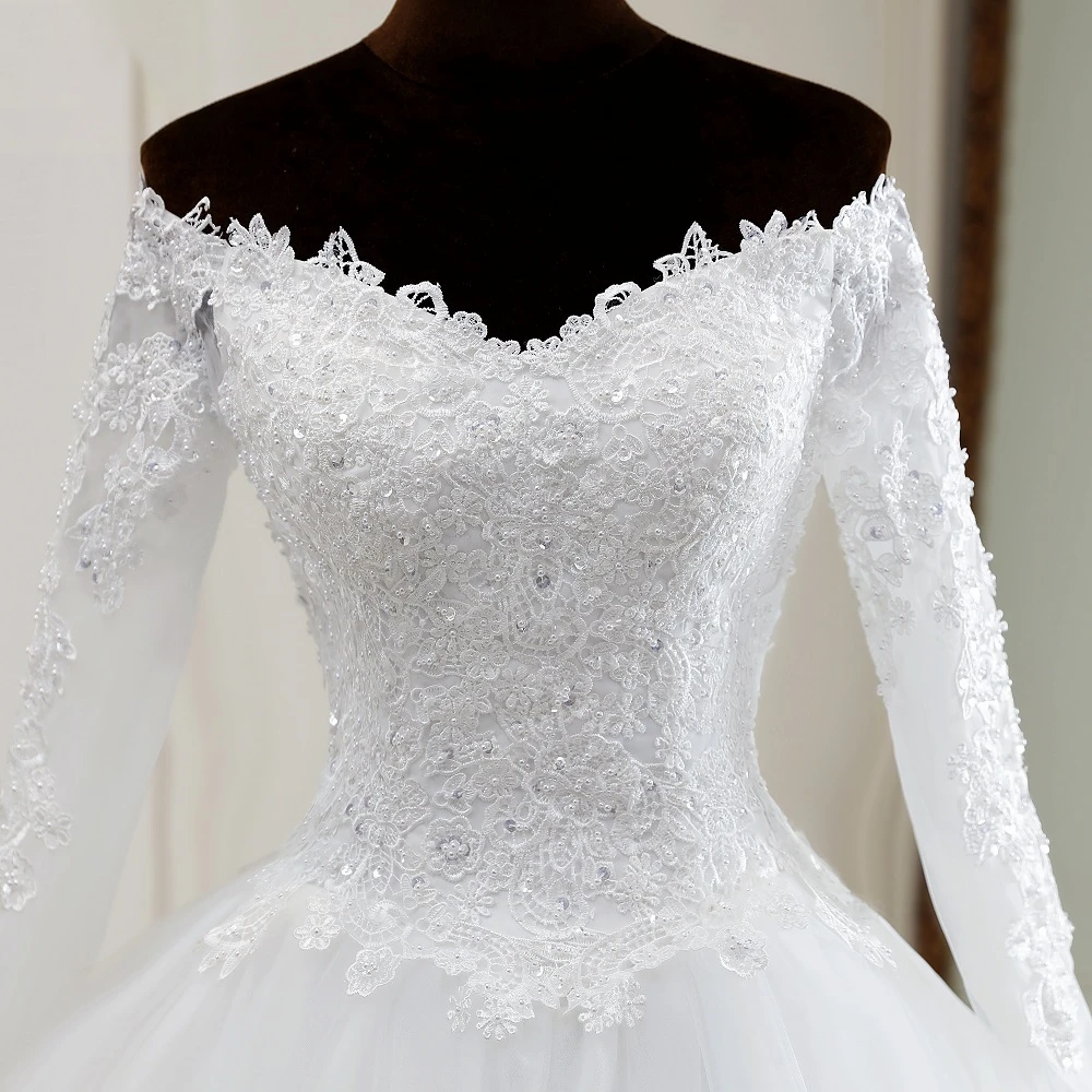 A detailed close-up shot of the intricate lace and sequin embroidery on the sleeves and bodice of an off-shoulder wedding gown.