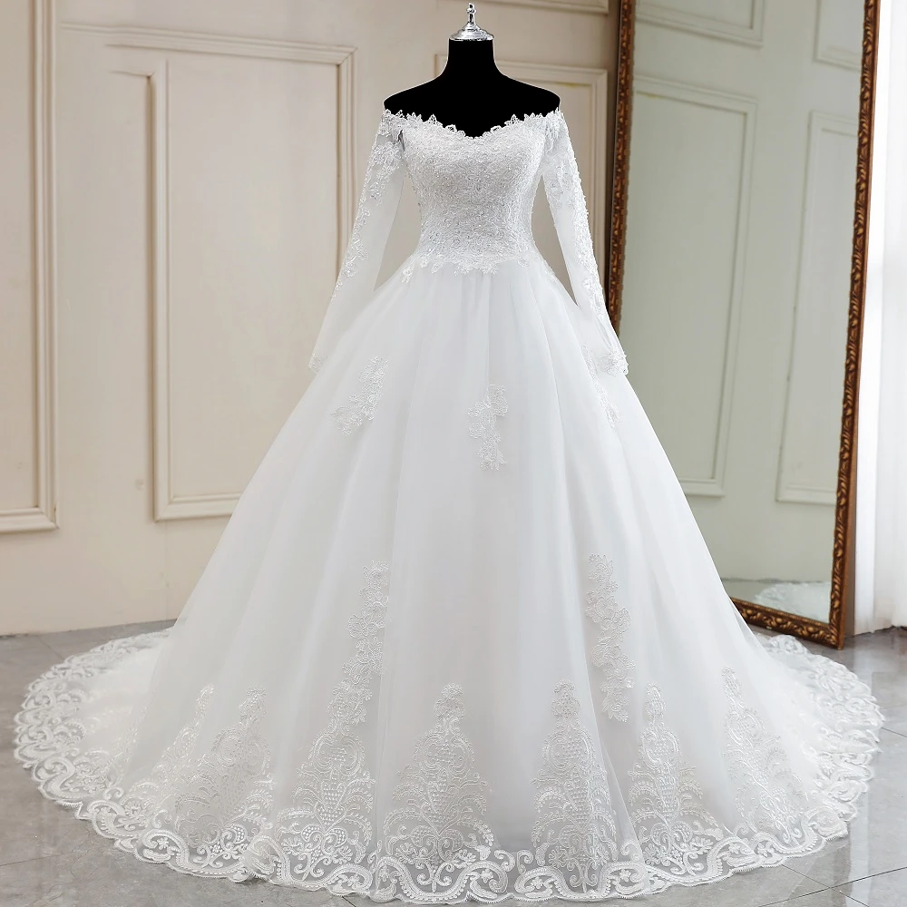 A mannequin showcasing the front view of a luxury, long-sleeve, off-shoulder lace wedding dress with a full, flowing bridal skirt.