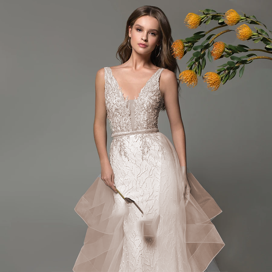 Front view of a shimmering beaded mermaid wedding gown with a V-neckline and detachable train, styled with floral elements.