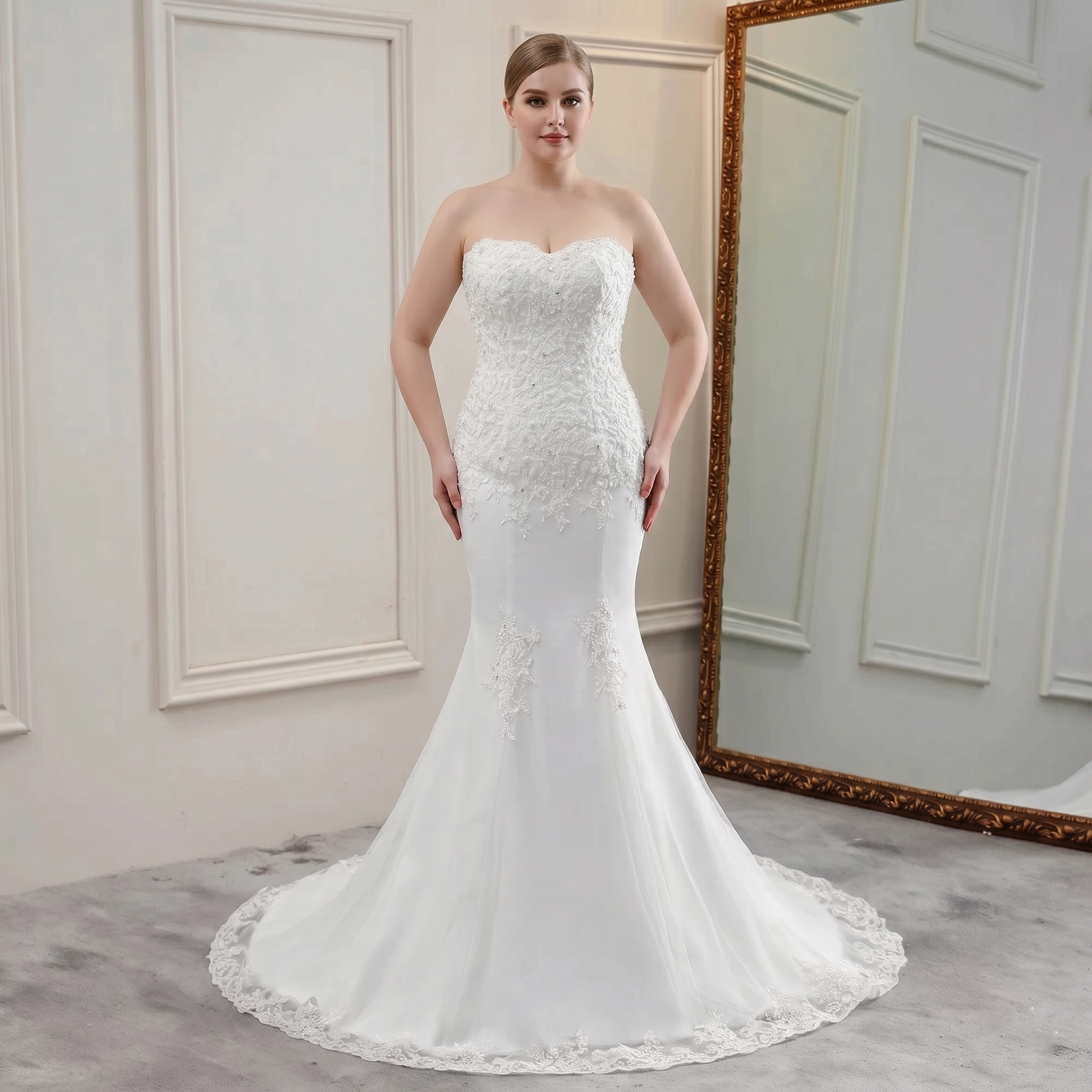 Front view of a bride modeling a beautiful strapless mermaid bridal gown with beaded bodice and lace appliques.