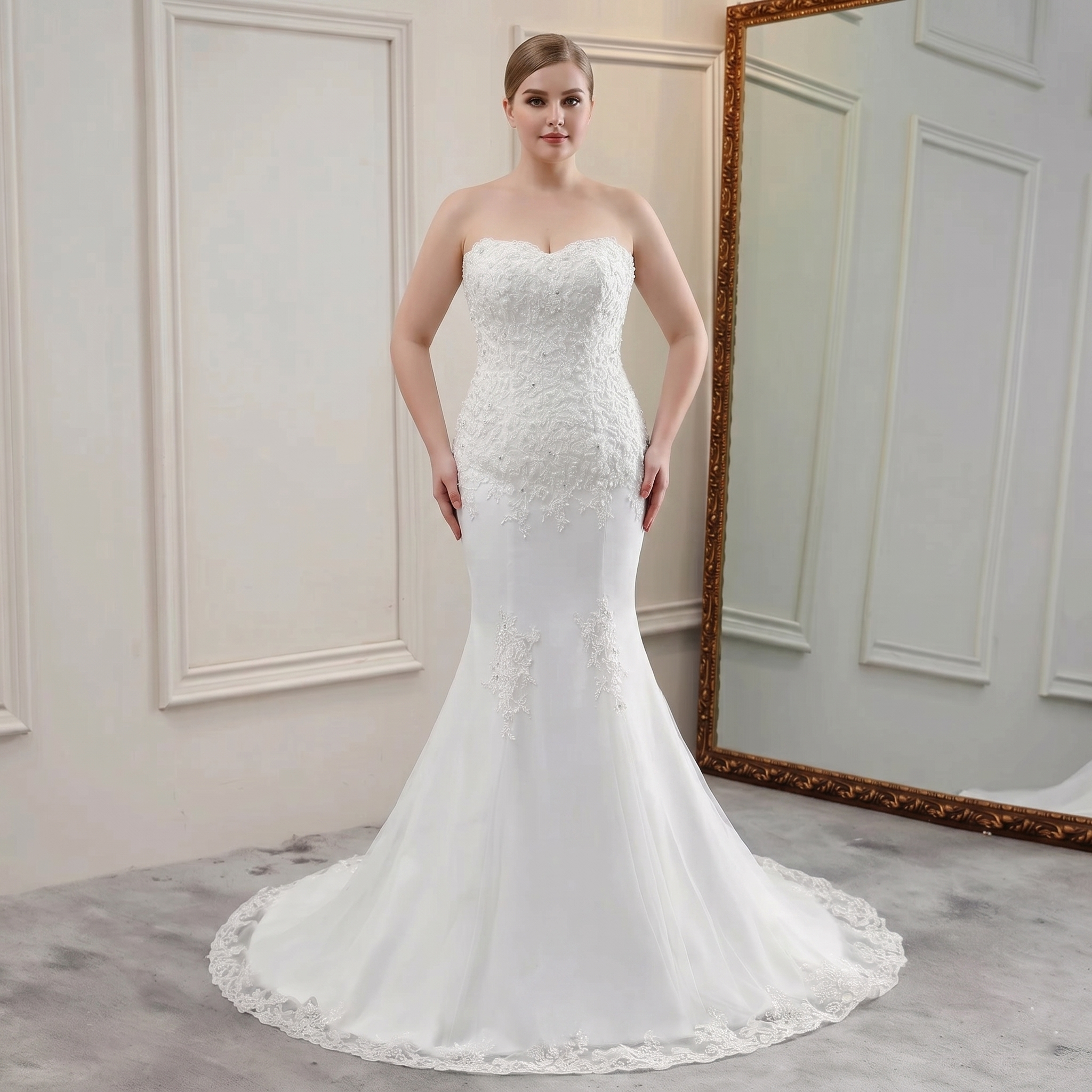 Front view of a bride modeling a beautiful strapless mermaid bridal gown with beaded bodice and lace appliques.