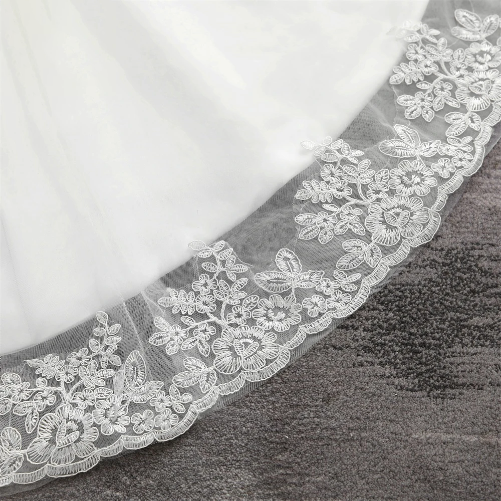 Close-up detail of the delicate floral lace hemline on a mermaid-style bridal gown.