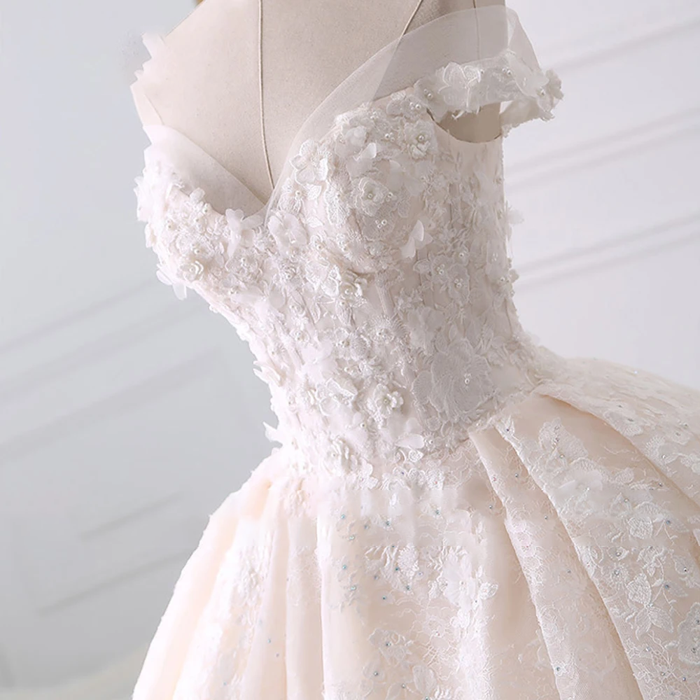 Close-up detail of the sweetheart neckline on a bridal ball gown, showcasing 3D flower appliques, delicate beadwork, and fine lace embroidery.
