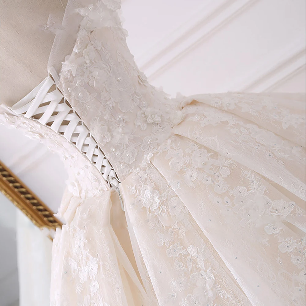 A close-up view of the bodice and corset back of a luxury ball gown wedding dress, featuring exquisite floral lace applique and beaded details.