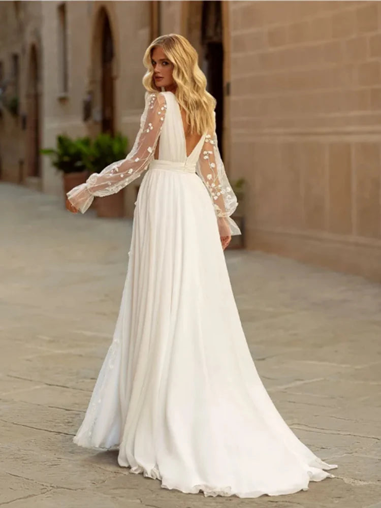 Elegant backless A-line wedding dress with sheer long sleeves and floral appliques, featuring a sweep train.