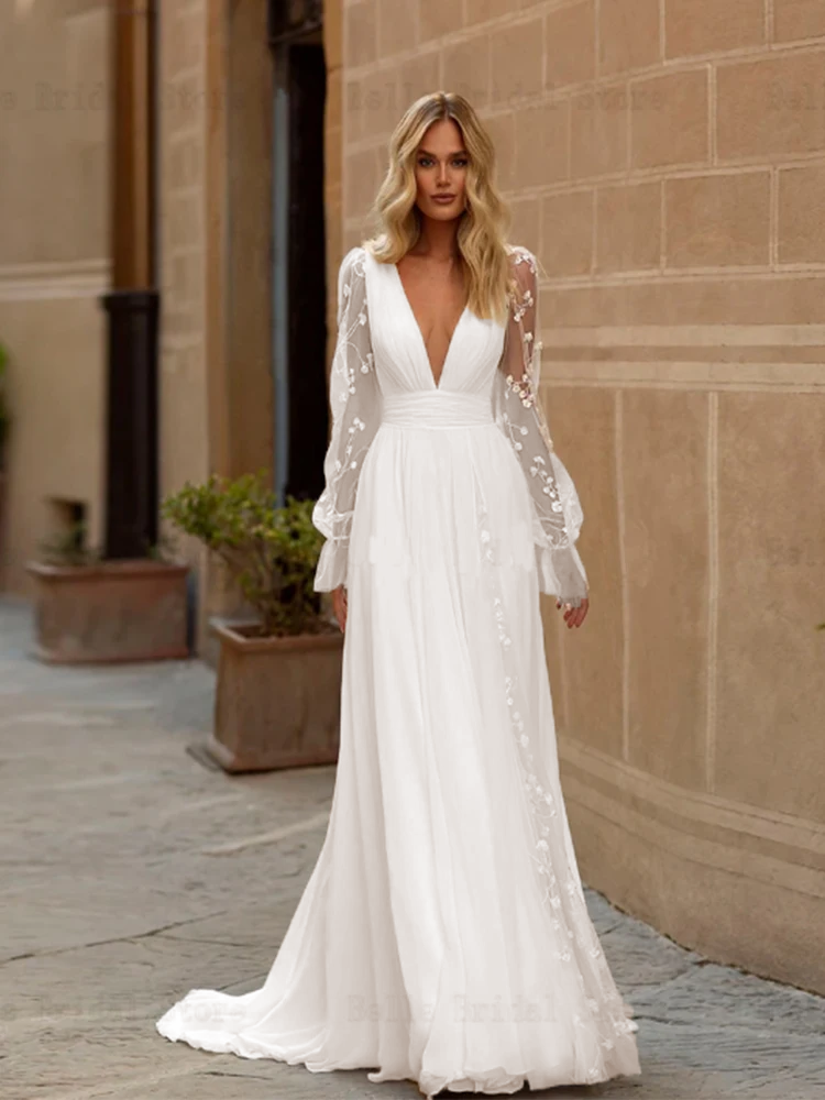 Front view of a sexy A-line bridal gown with a deep V-neck, sheer long sleeves with appliques, and an elegant sweep train.