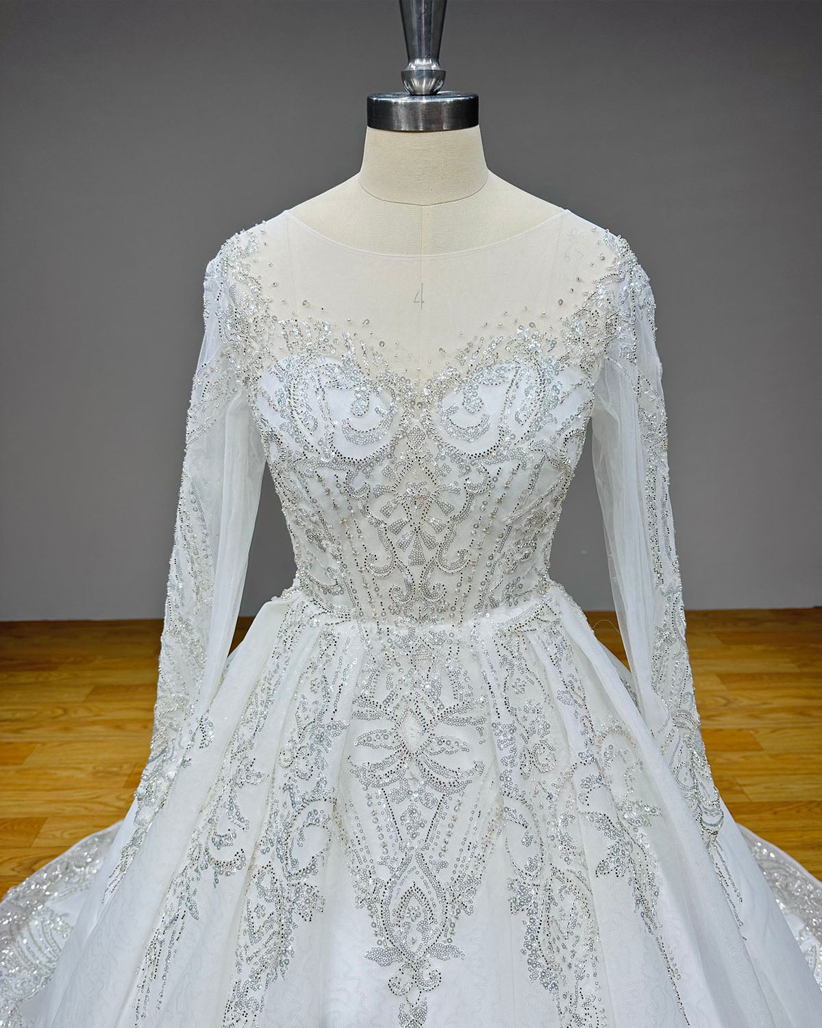 Straight-on front close-up of a luxury wedding gown bodice on a mannequin, detailing the symmetrical sequin patterns and shimmering beadwork over a sweetheart inner lining.