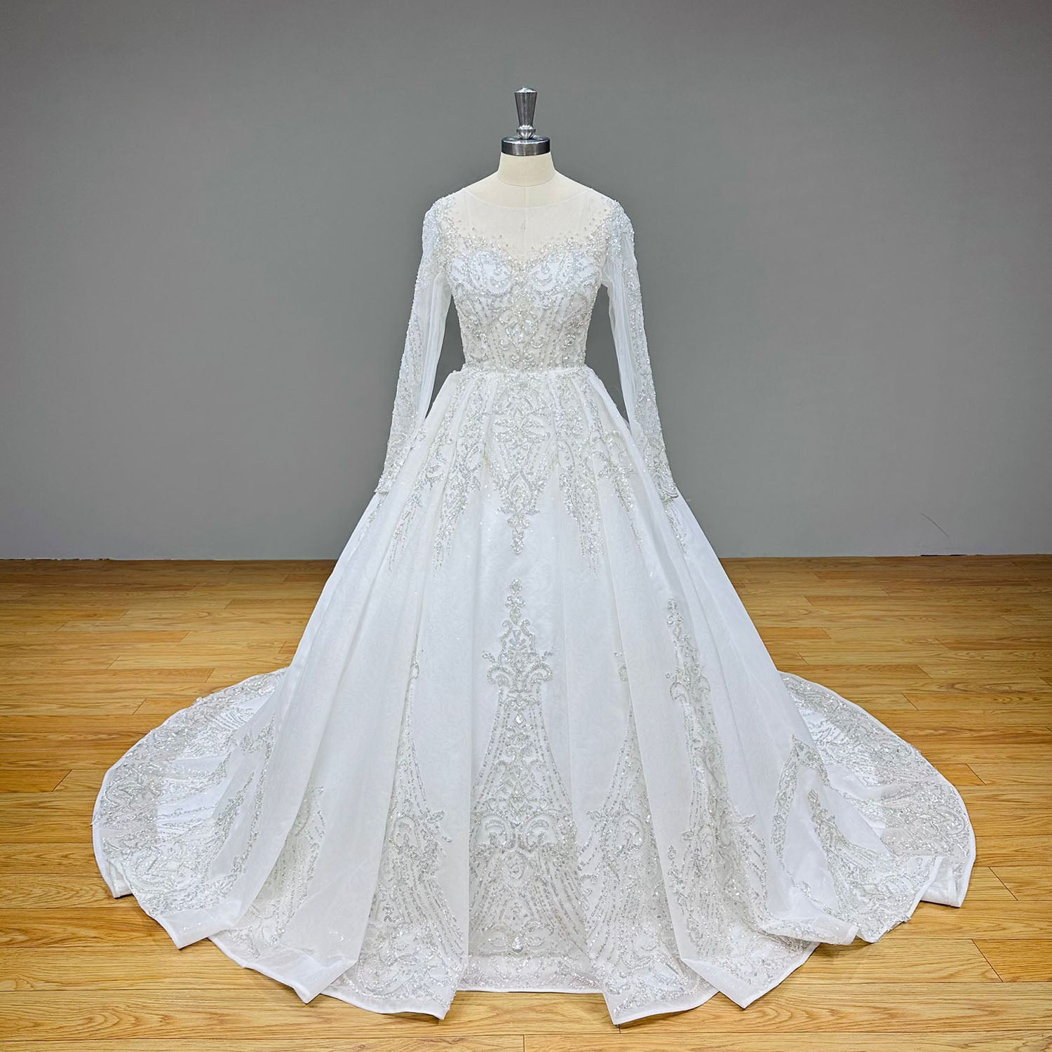 Full-length front view of a sparkly long sleeve ball gown wedding dress with heavily embellished sequined details on a studio mannequin.