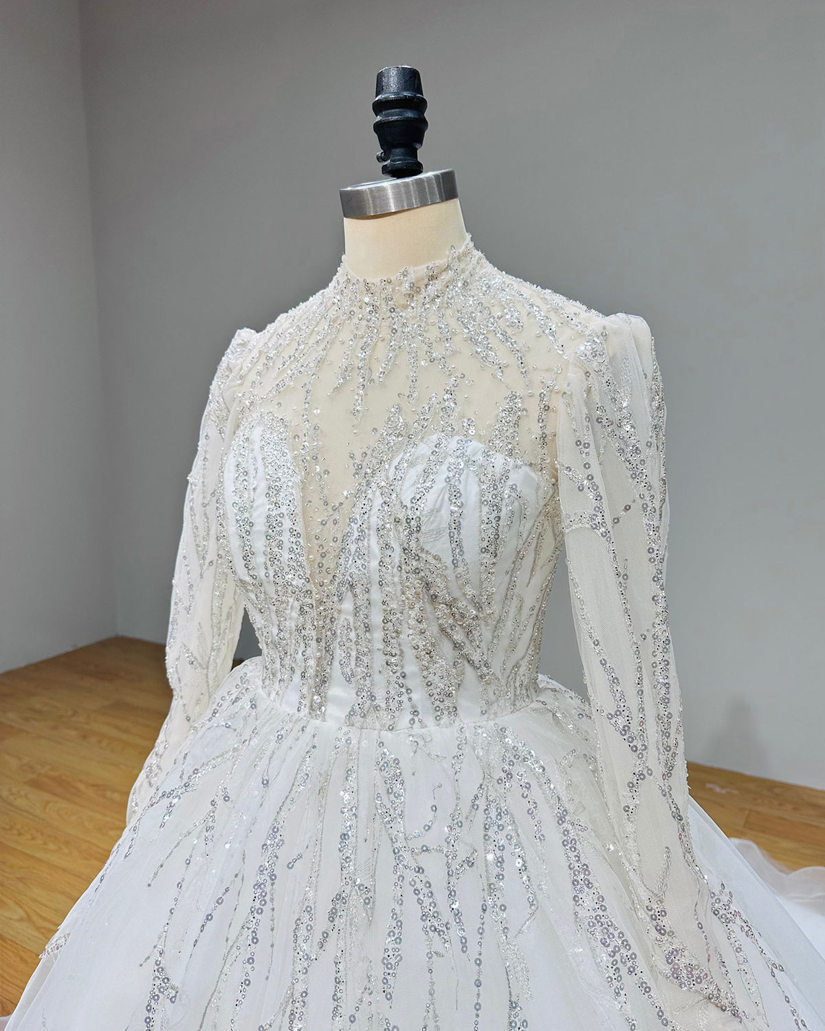 Detailed three-quarter view of a high neck wedding dress bodice featuring clear illusion fabric and linear sequin branch art.