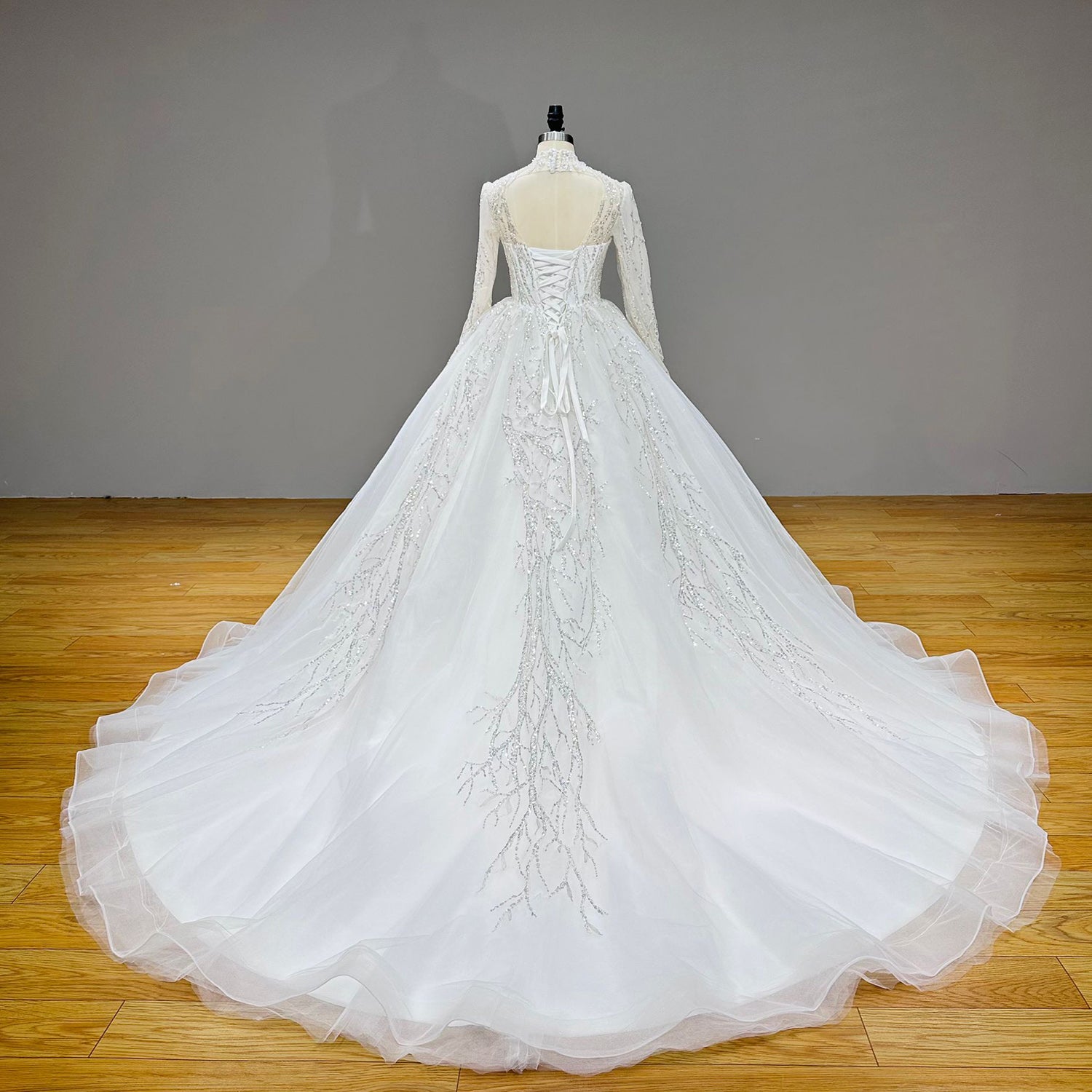 Full back product shot of a backless luxury wedding dress on a mannequin, showcasing a sprawling branching sequin train.