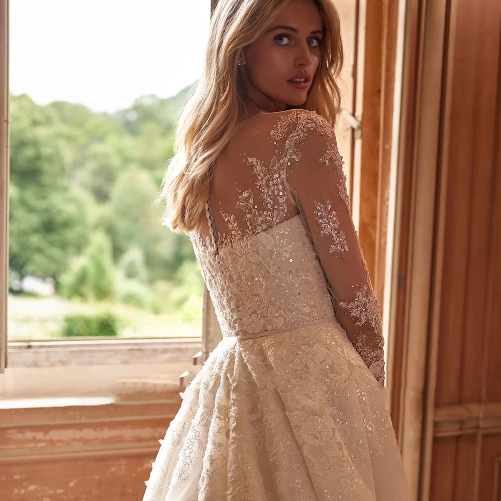 Rear view detail of a luxury wedding gown highlighting a sheer illusion back adorned with delicate sequin appliques and a row of classic bridal buttons.