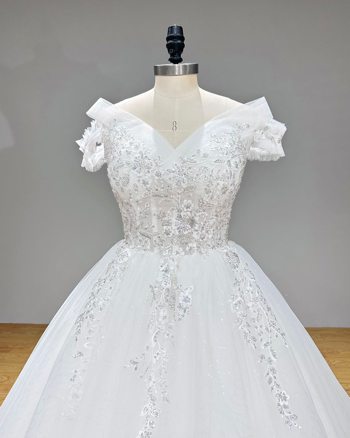 Front close-up view of a structured sweetheart neckline bridal bodice with dense sequin beadwork and sheer corset panels on a studio dress form.