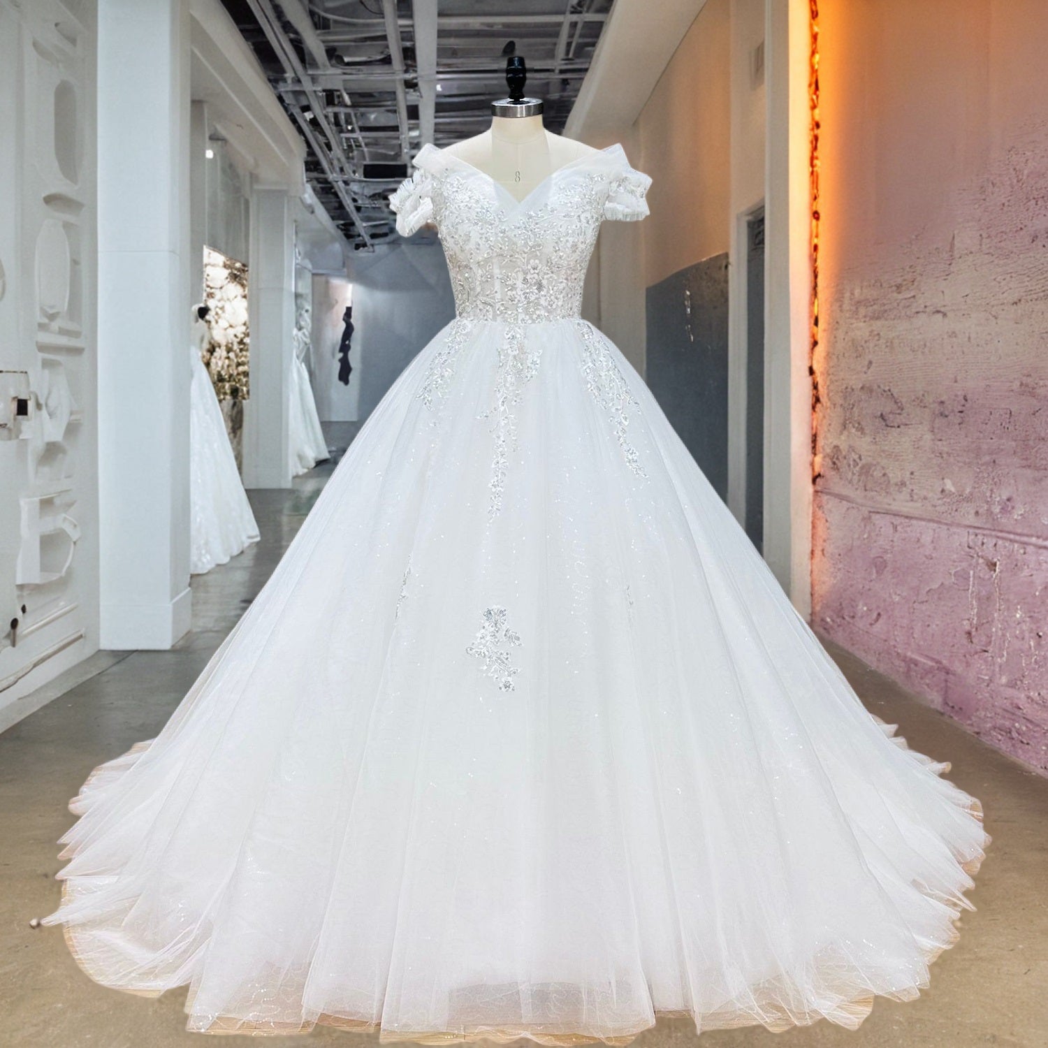 Sparkling white off-the-shoulder princess ball gown bridal dress featuring intricate sequined lace details on a mannequin in an upscale boutique corridor.