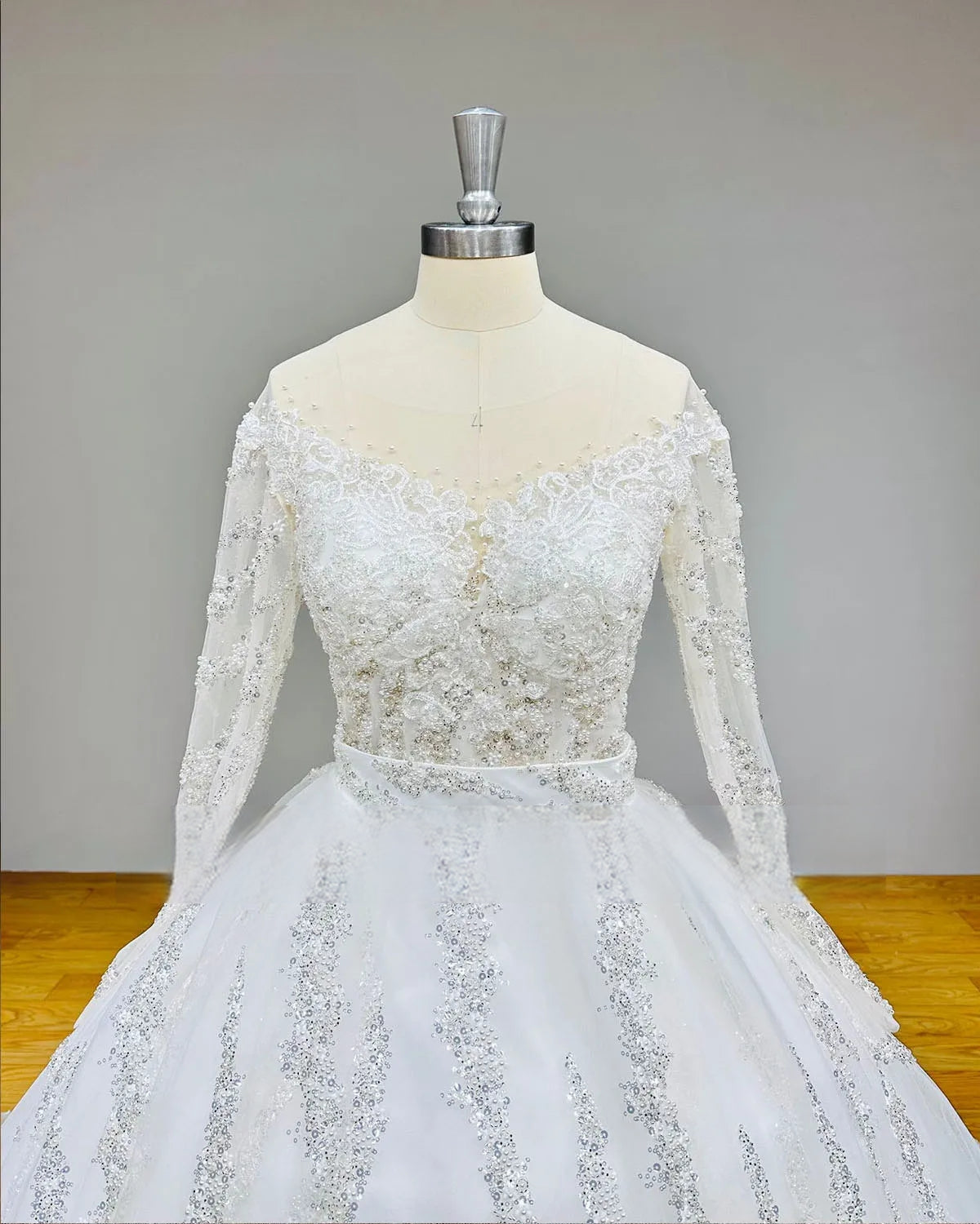 Close-up detail of the front bodice of the shiny beaded wedding dress showcasing intricate sequin embroidery and a delicate illusion neckline.
