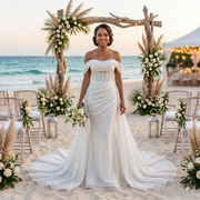 Glamorous bride wearing a shiny beaded off-the-shoulder mermaid wedding dress with a sheer corset bodice and detachable tulle train at a luxury beach ceremony.