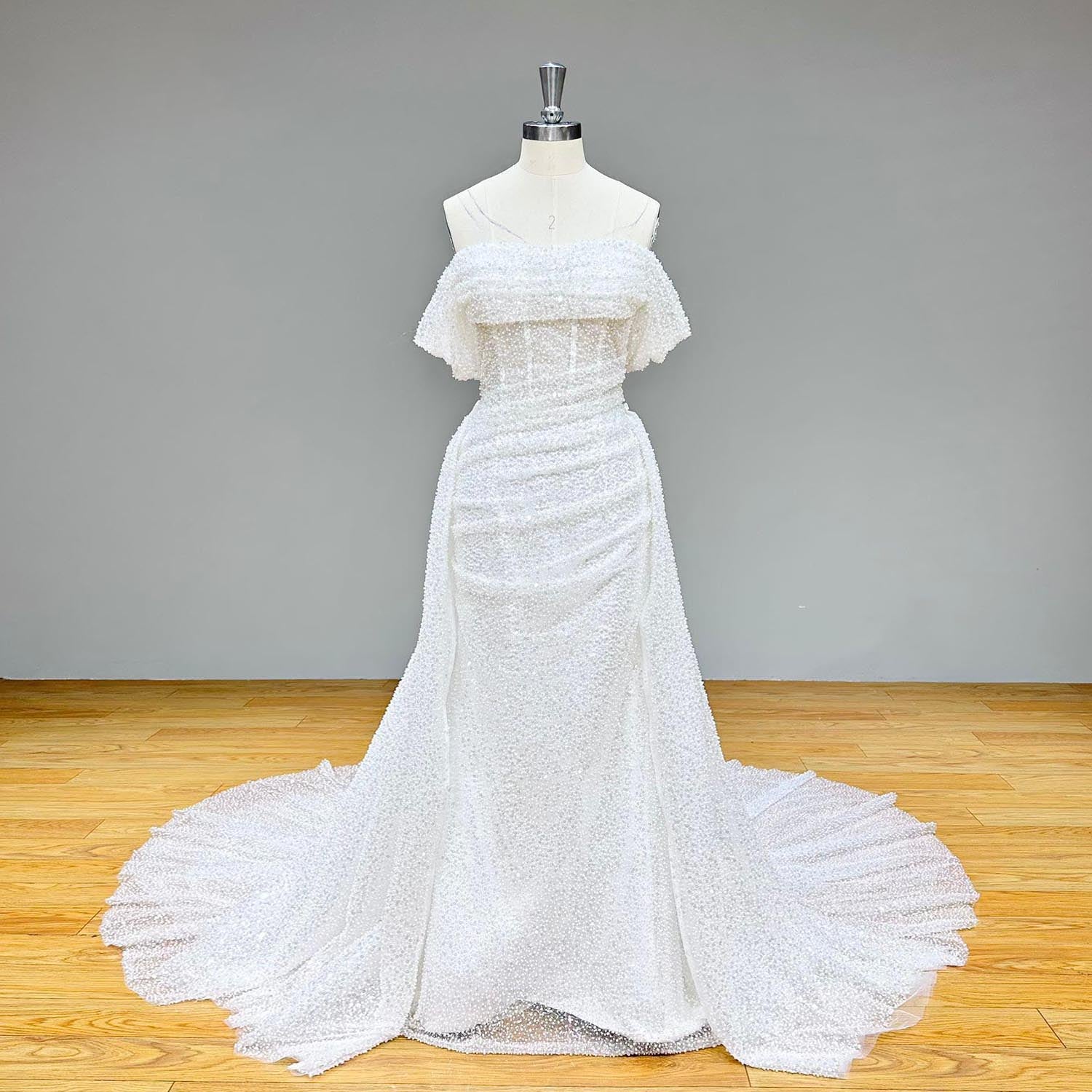 Full-length front studio view of a dazzling white sequin and bead-embellished tulle mermaid wedding gown on a mannequin without the overskirt.