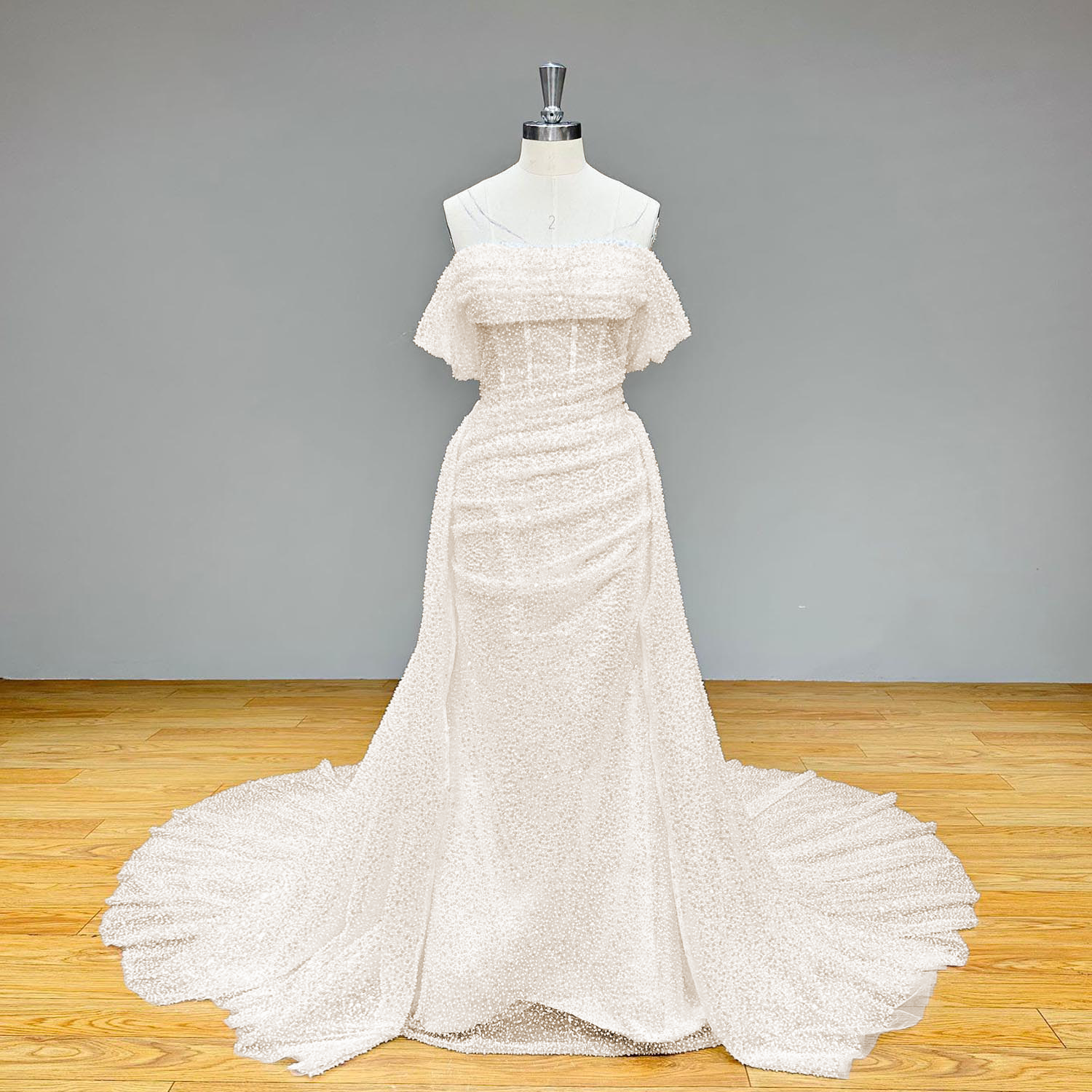 Full-length front studio view of a dazzling white sequin and bead-embellished tulle mermaid wedding gown on a mannequin without the overskirt.