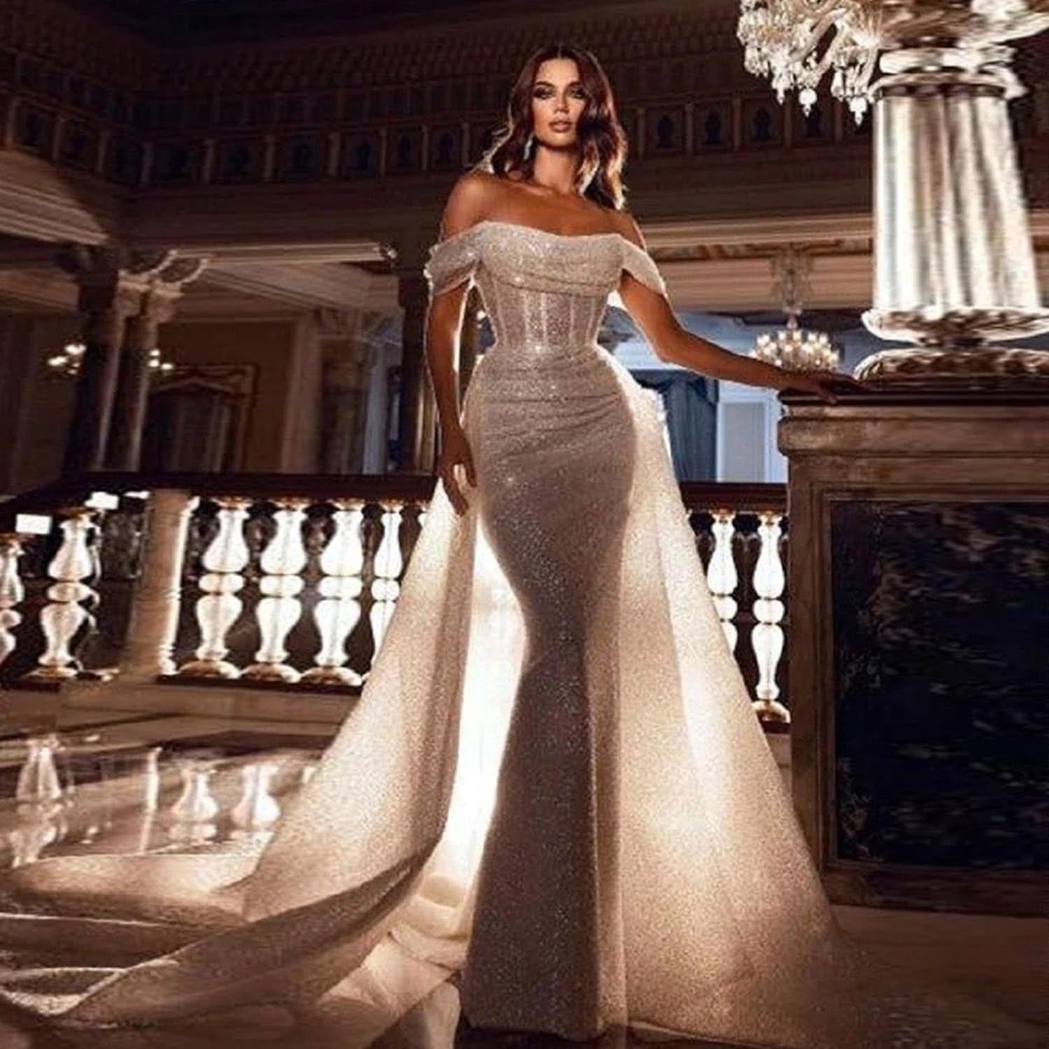 Elegant model posing on a grand mansion staircase in a high-shine beaded mermaid wedding dress with an expansive, dramatic detachable train.