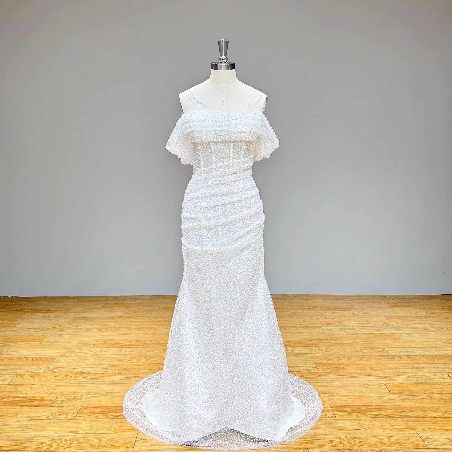 Full-length front studio view of a dazzling white sequin and bead-embellished tulle mermaid wedding gown on a mannequin without the overskirt.