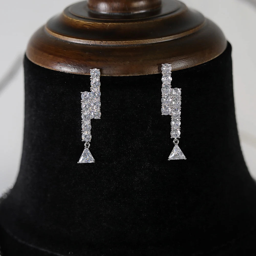 Close-up view of the elegant geometric zigzag cubic zirconia dropdown statement earrings on a black display stand.