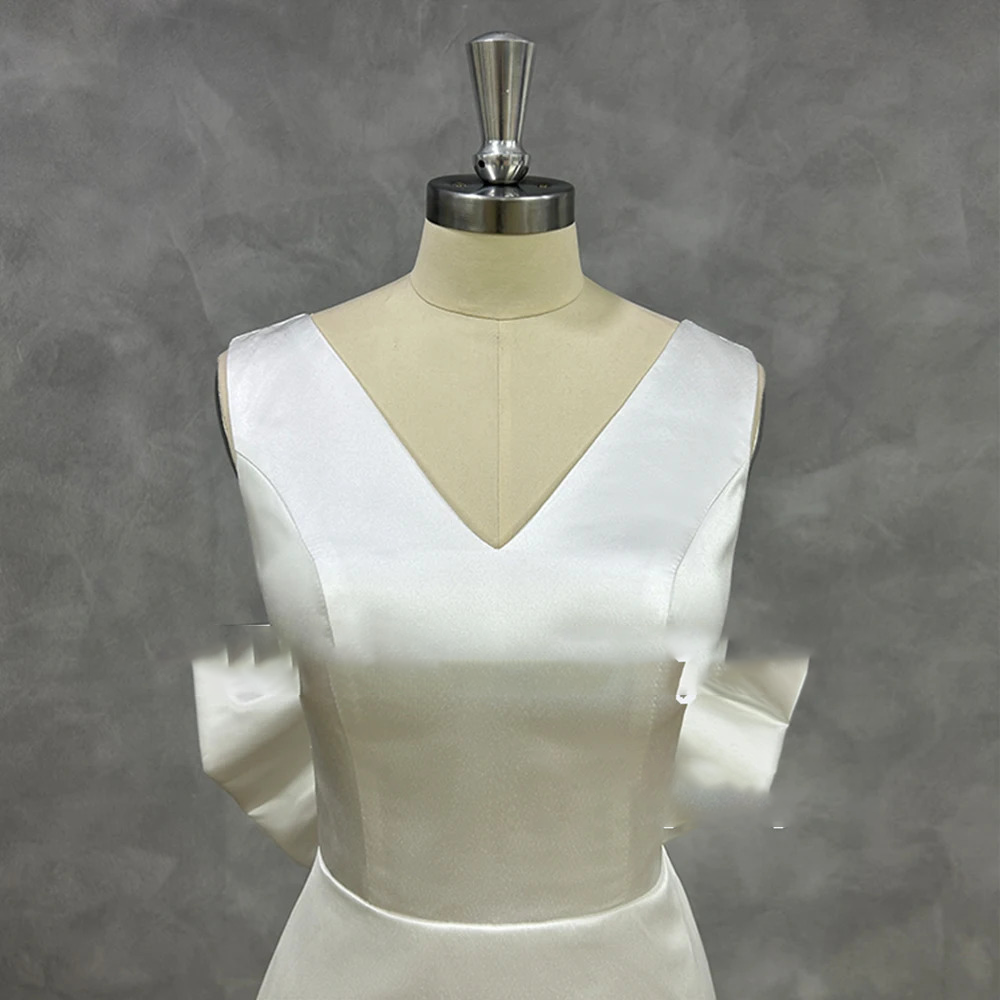 Detailed front shot of a minimalist white satin bridal bodice on a mannequin, highlighting clean princess seams and a tailored plunging V-neckline.