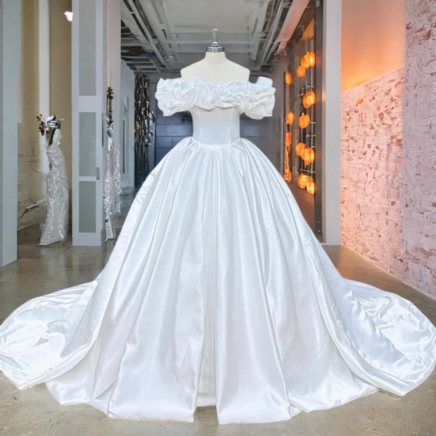 Mannequin display of a white matte finish satin wedding gown with off-the-shoulder ruffled sleeves and a classic ball gown silhouette in a bridal boutique.