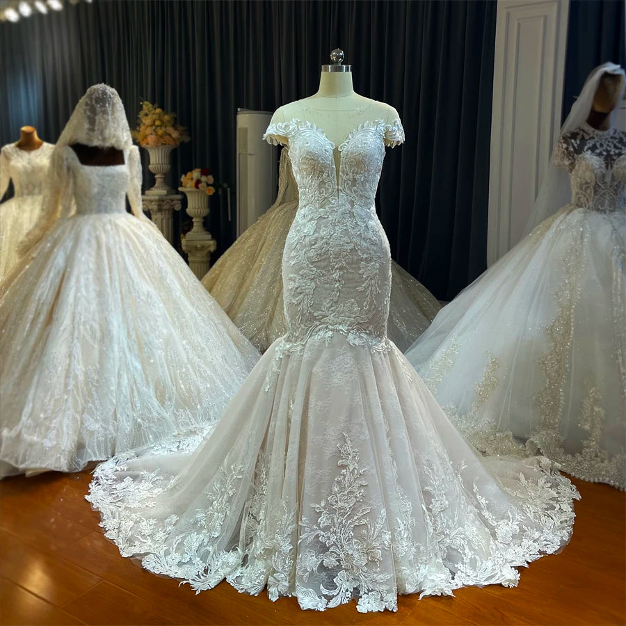 Front view of an elegant, flowy mermaid bridal gown on a mannequin, showcasing the light floral lace appliqués and deep V-neckline.