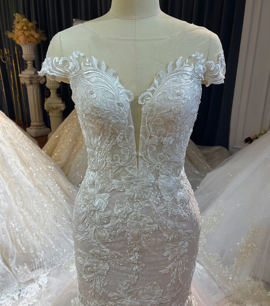 Close-up detail of the plunging V-neckline and intricate floral lace bodice on a simple beach-style light wedding dress.