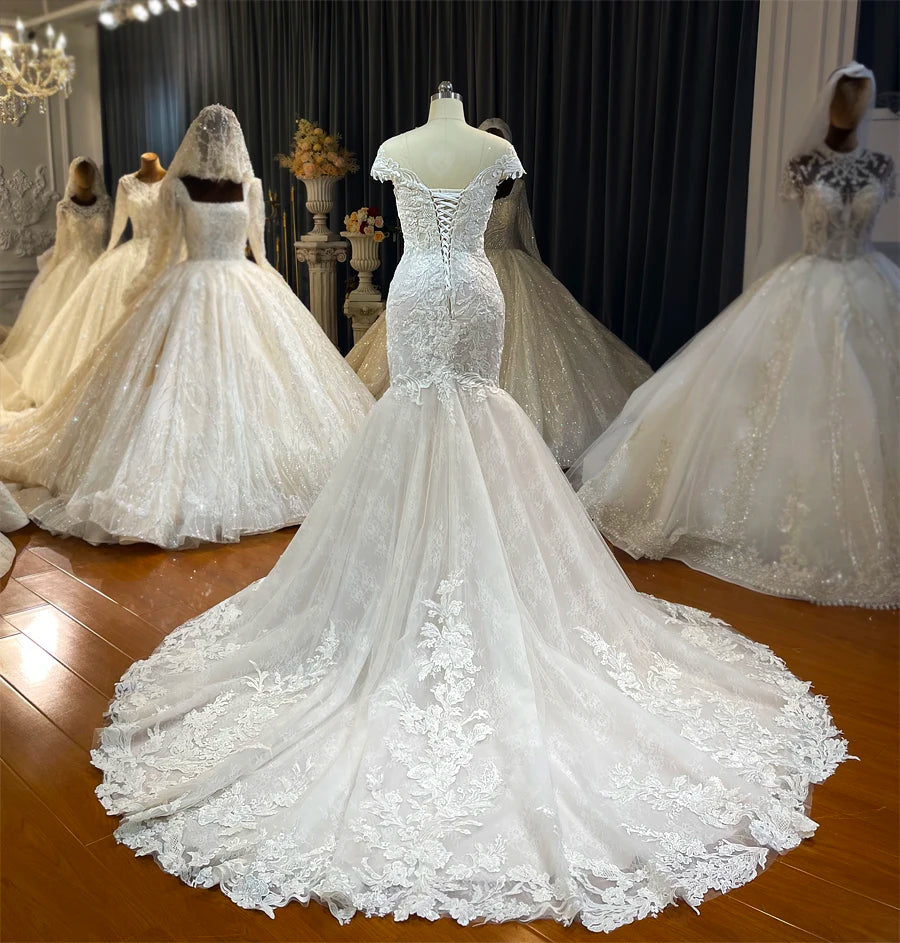 Rear view of the light and flowy mermaid wedding dress on a mannequin, highlighting the classic corset lace-up back and the wide, elegant lace-trimmed train.