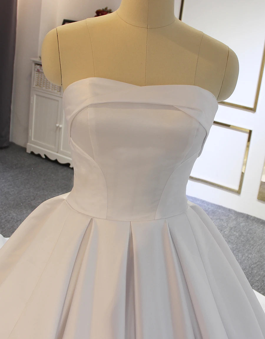 Detailed close-up of a minimalist strapless bridal bodice made of high-quality off-white satin, featuring a modern clean-cut design and structured waistline.