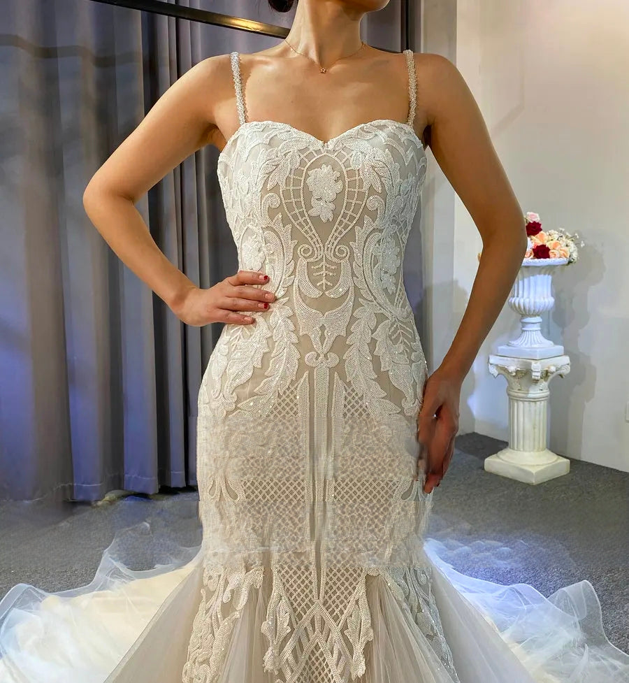 Rear view of the slim lace bridal gown on a mannequin, featuring a traditional lace-up corset back and an expansive, romantic cathedral-length lace train.