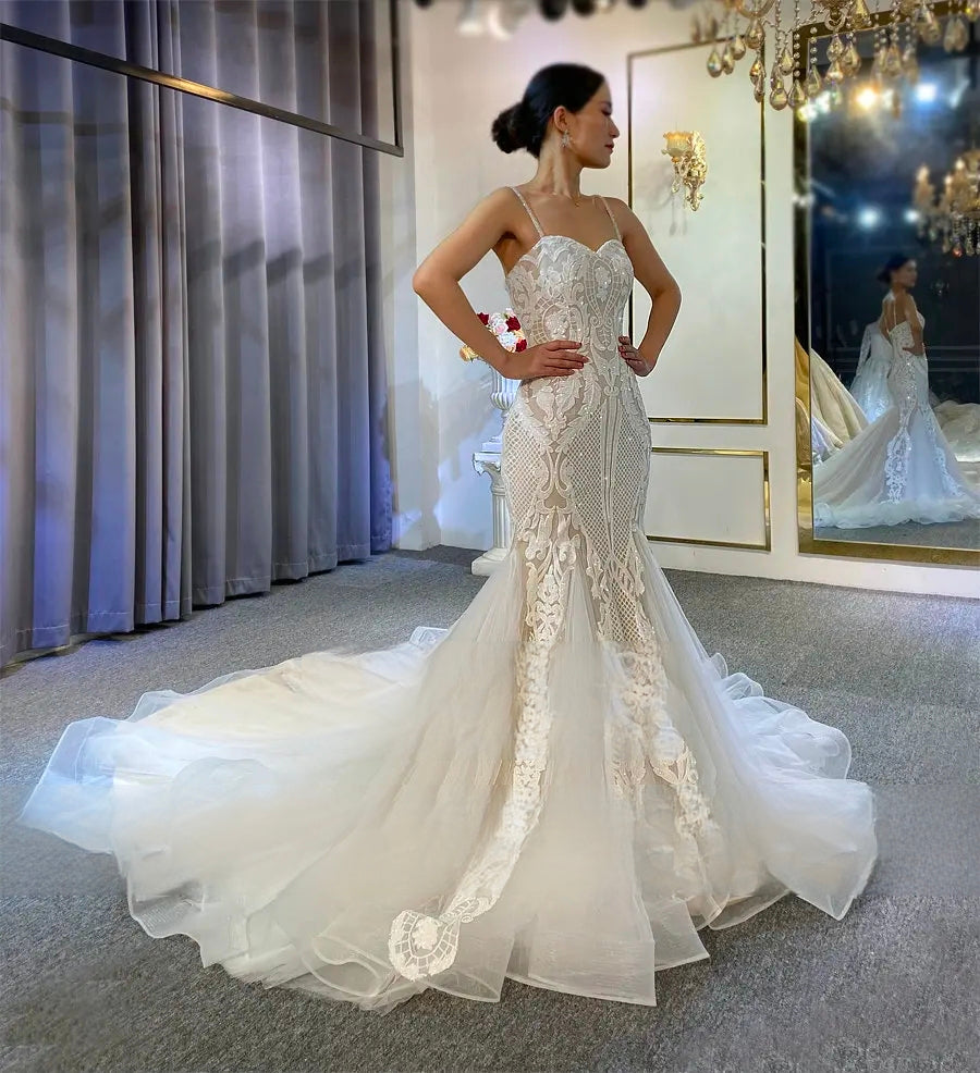 Full-length view of the slim lace wedding gown from the back, showcasing the grand spread of the ornate floral lace train in a luxury bridal showroom.