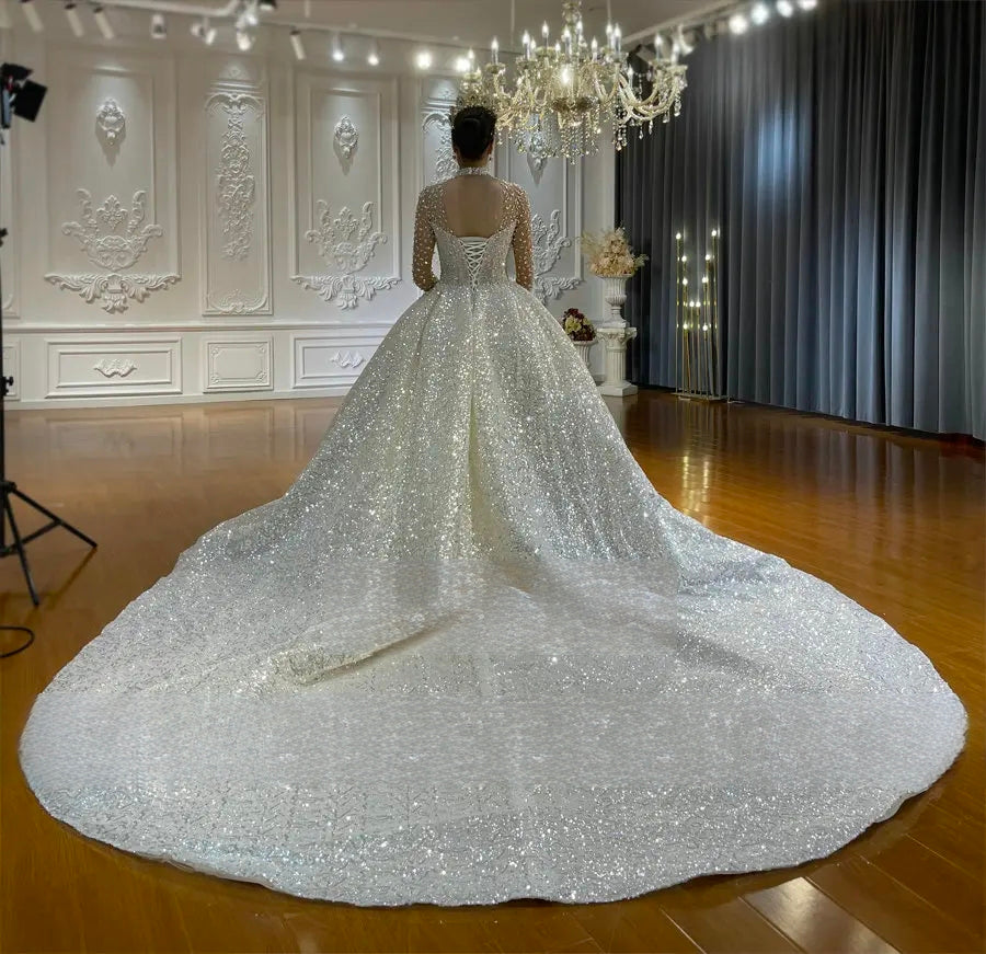Wide-angle rear perspective of a luxury princess wedding dress, highlighting the majestic spread of the cathedral-length sparkling train and the elegant illusion back detailing.