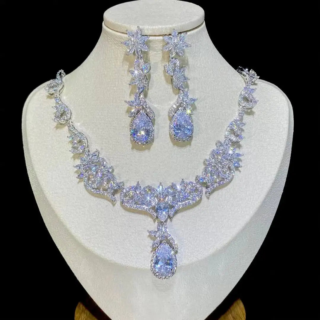 Front view of a brilliant zircon crystal wedding necklace and long dropdown earrings set on a white jewelry stand.