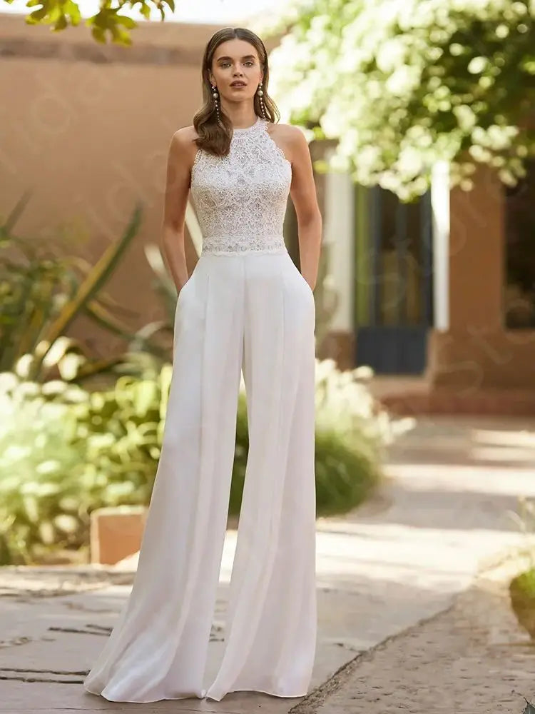 Elegant front shot of the sleeveless spring lace bridal jumpsuit, emphasizing the high-waisted tailoring and intricate lace patterns across the halter neck bodice.