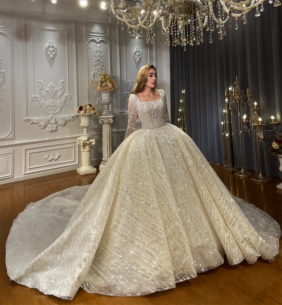 Side profile of a shimmering long sleeve wedding ball gown highlighting the textured vertical sparkle detailing and the wide sweep of the fluffy skirt.