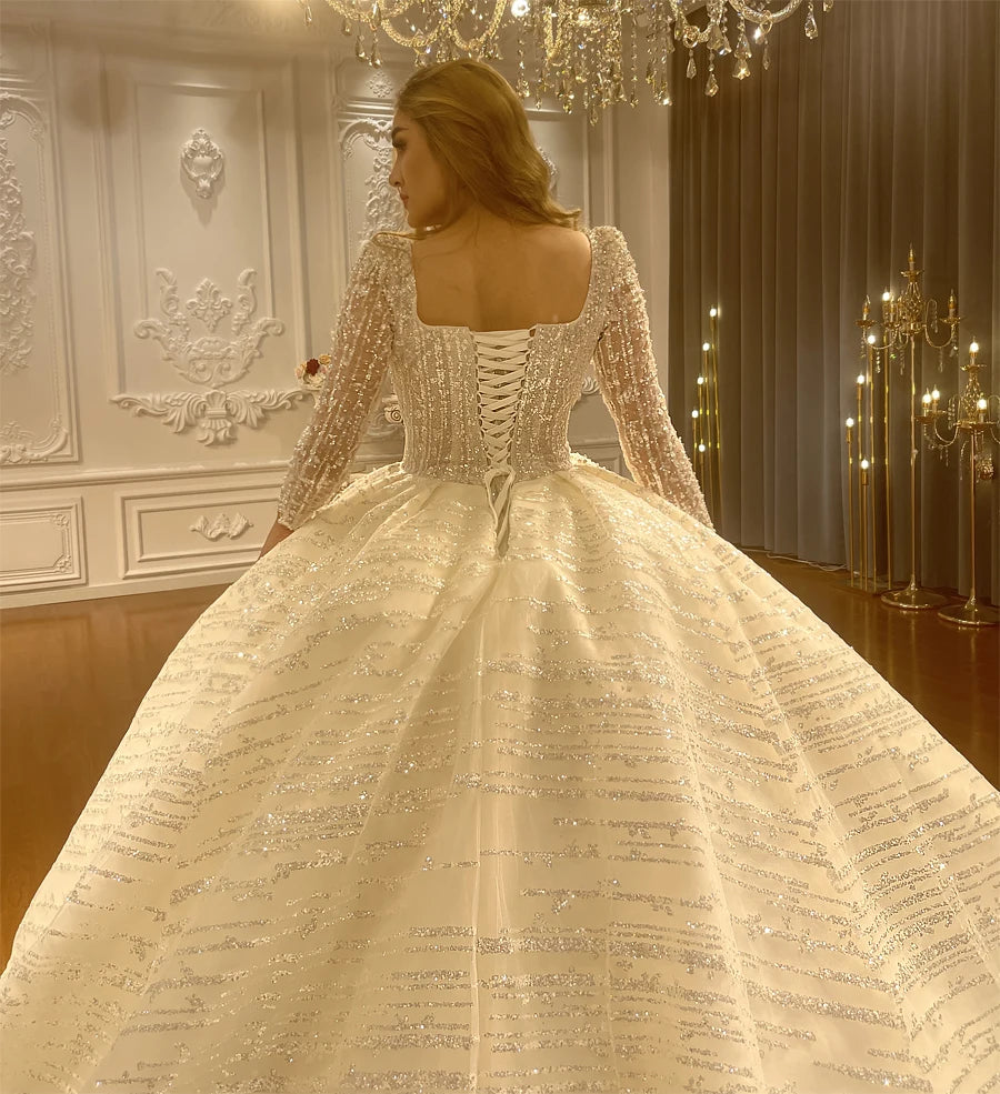 Rear view of a luxury bridal gown showing the elegant square back design, adjustable lace-up corset closure, and heavy beading on the shoulders.