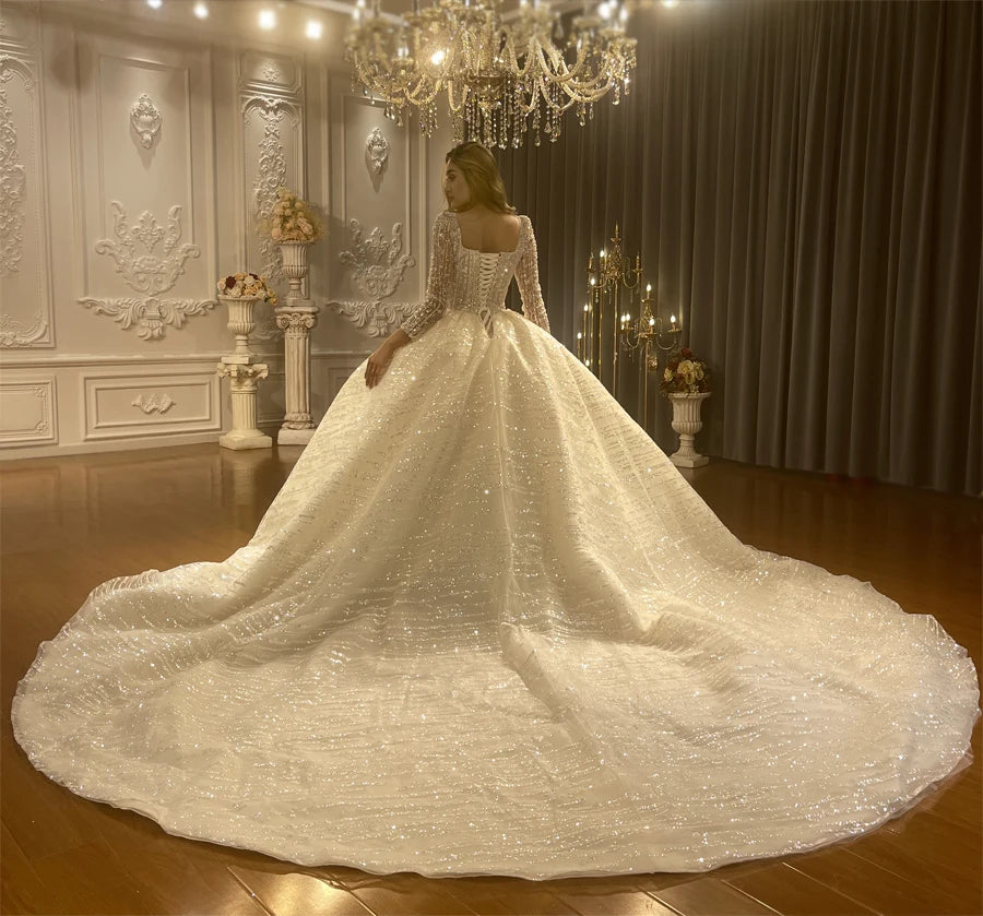 Full back view of a luxury ball gown wedding dress showcasing a massive shimmering cathedral train and an expansive fluffy princess silhouette.