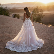 A bride wearing a sleeveless A-line wedding dress with a square neckline and a shining tulle surface, captured in a scenic outdoor setting.