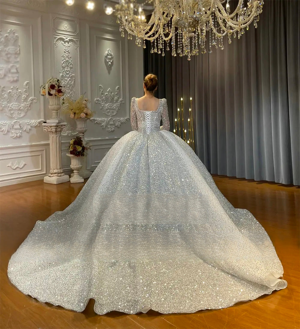 Rear view of a sparkly ball gown wedding dress showcasing an elegant lace-up corset back and a magnificent, wide-reaching cathedral-length sequined train.