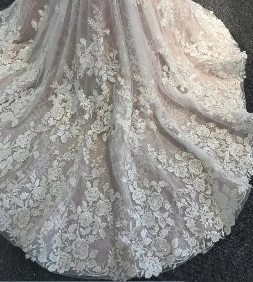 Detailed shot of the intricate floral lace embroidery and scalloped edges on the train of an elegant mermaid wedding dress.