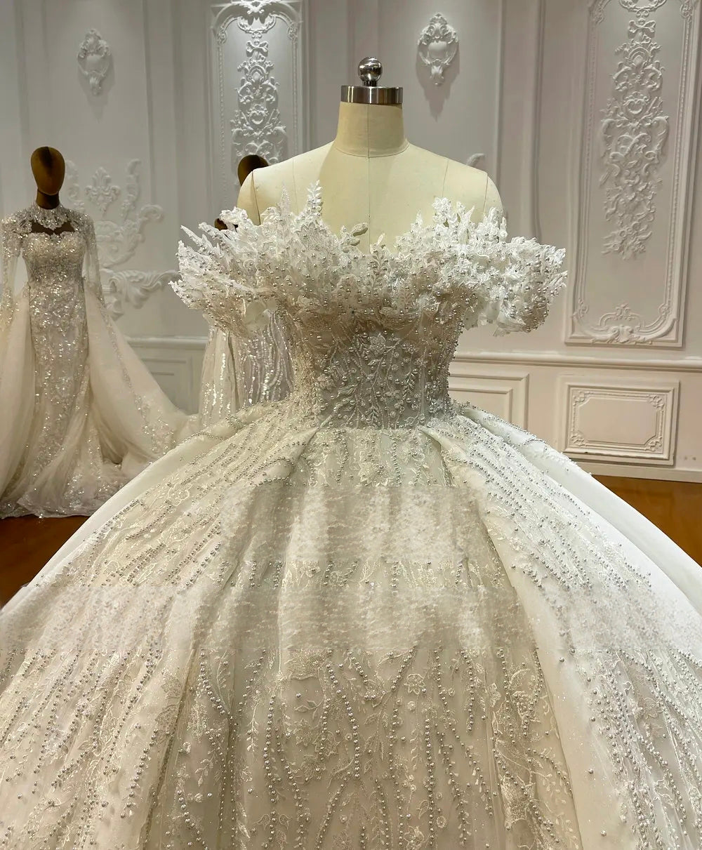 Detailed close-up of a 3D floral lace off-the-shoulder bodice with heavy crystal embellishments and beaded accents for a high-end luxury bridal look.
