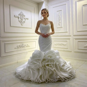 Front view of a blonde model wearing a strapless mermaid wedding dress with a pleated sweetheart bodice and a voluminous tiered organza ruffle skirt.