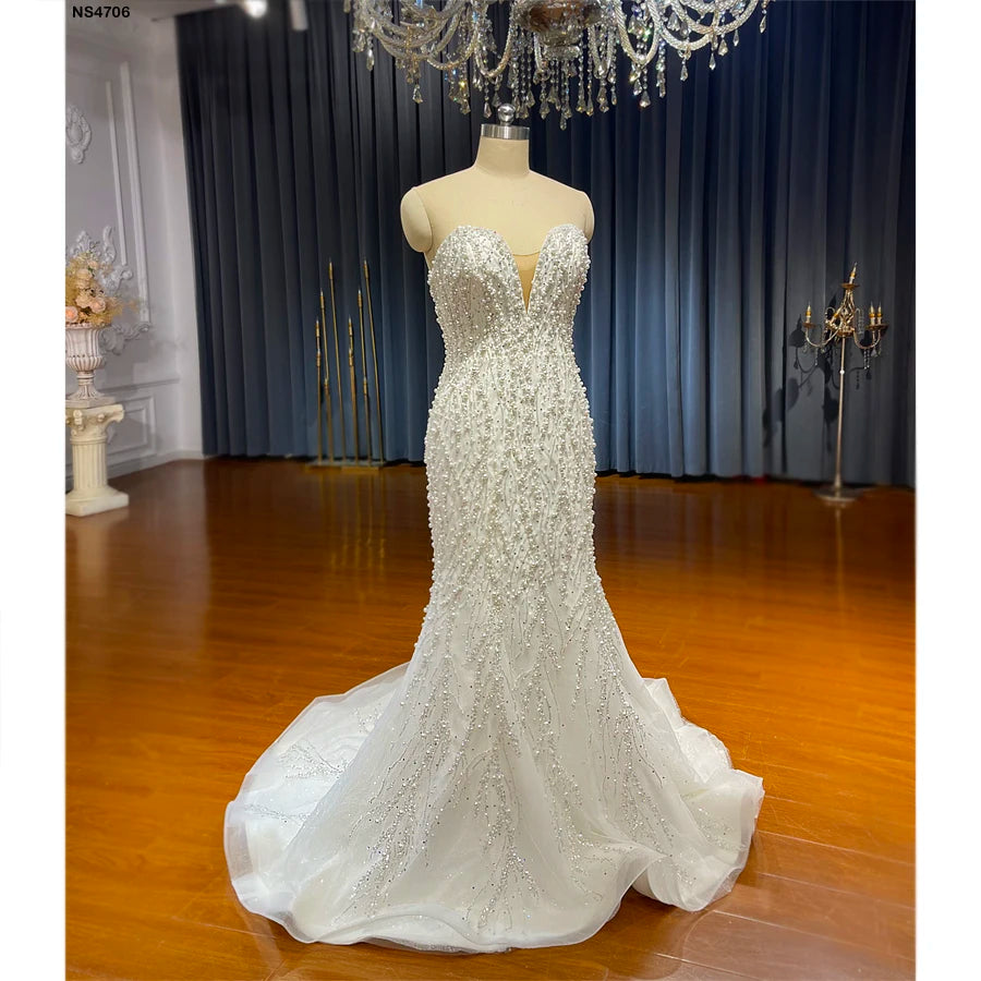 A front-side angle of the strapless slim mermaid wedding dress on a mannequin, showcasing the fitted silhouette and the shimmering beaded patterns cascading down the skirt.